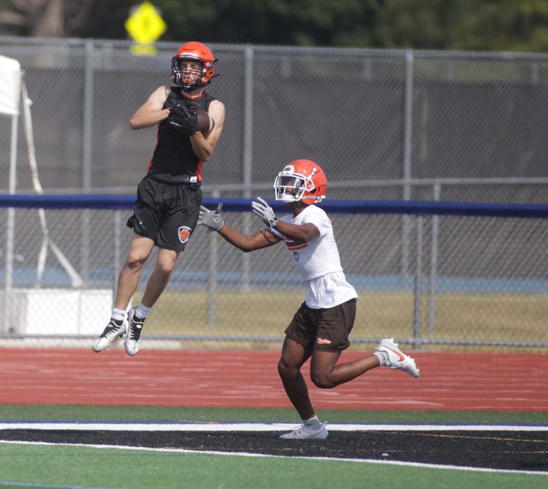 Wheaton Warrenville South’s Aidan Dalby (left) makes a catch during a 7-on-7 football game against Hersey at St. Charles North on Thursday, June 22, 2023.