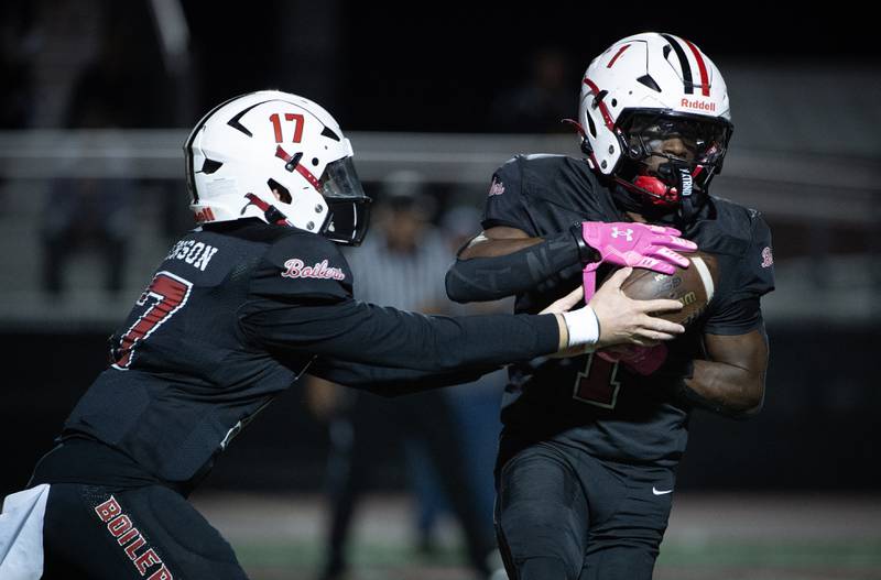 Bradley-Bourbonnais' Ellis Johnson, left, hands the ball off to Kyren Edmon in a game against Dekalb on Friday, October 10, 2025.