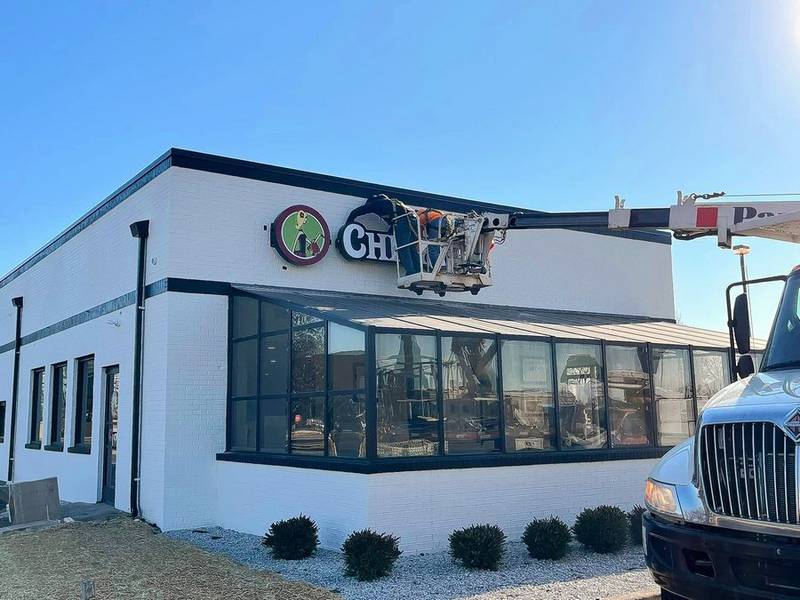 A worker installs the new Chicken Salad Chick restaurant sign outside of the Batavia building that once housed Crabby Boil.