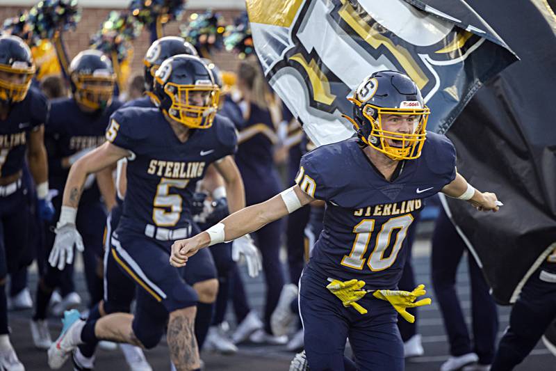 Sterling’s Cale Ledergerber bursts through a banner at the start of the game against St. Francis Friday, Sept. 1, 2023 at Sterling High School.