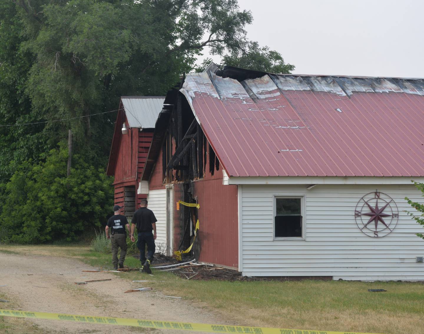 State Fire Marshal investigators walk by one of the damaged outbuildings Friday evening in the 9000 block of East High Road after a nearby home was destroyed in an explosion.