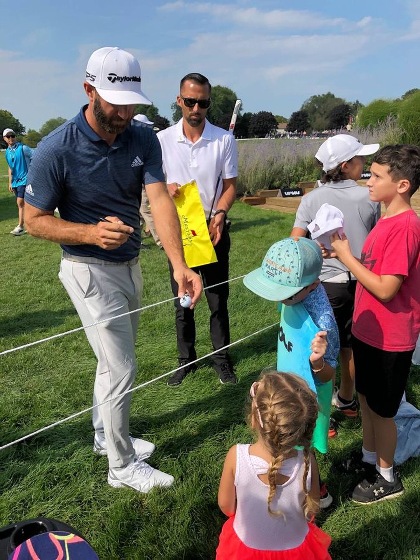Dustin Johnson hands a girl back her golf ball after he autographed it Friday at the LIV Golf tournament at Rich Harvest Farms in Sugar Grove.