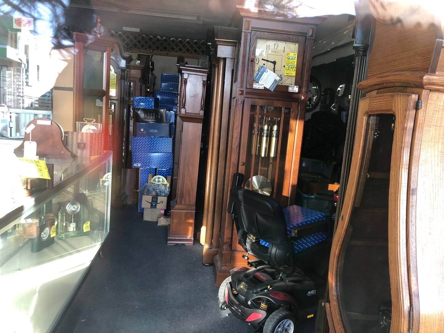 Grandfather clocks and other timepieces can be seen on March 11, 2025, through the window of The owner of McHenry Clock Co. in McHenry.