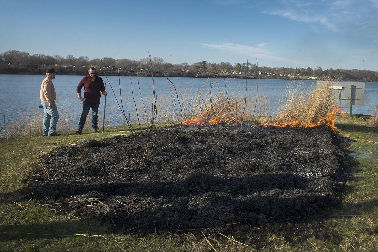 To celebrate Keller and his work, Rick O'Neil (left) and Kyle Sommers oversaw a small prairie burn in the Rock Falls natural grass area.  The area is located right where the canal and Rock River meet.