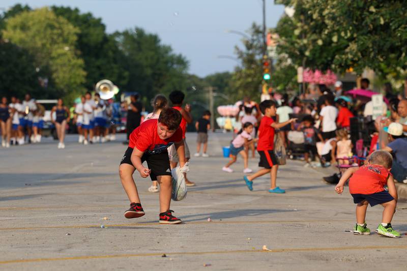 Declan Young, 5, left, of Momence, races to collect candy during the 87th Momence Gladiolus Festival Main Street Parade on Friday, Aug. 8, 2025.