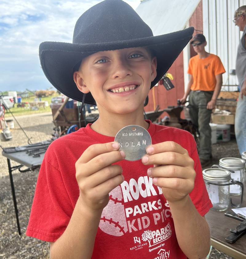 Nolan Huber, 9, of Milan, shows the metal badge he made with his initials on it under the direction of Daryl Drennen of Prophetstown at the Bos Bros. Historical Farm Old Fashioned Fall Harvest on Saturday, Sept. 21, 2024. Hands-on demonstrations gave kids the opportunity to try a variety of trade skills.