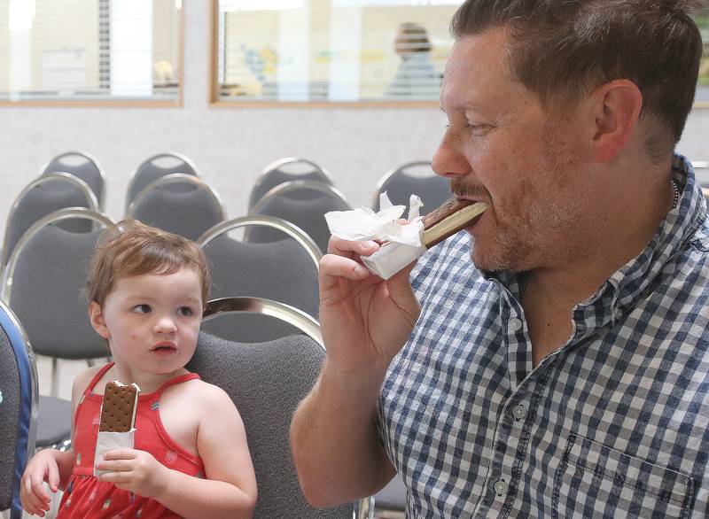 Oglesby mayor Jason Curran shares a ice cream bar with Remi Eichelkraut on Wednesday, Aug. 23, 2023 at the Oglesby City Hall. Mayor Curran celebrated his birthday by handing out free ice cream bars and popsicles as a treat to beat the heat.