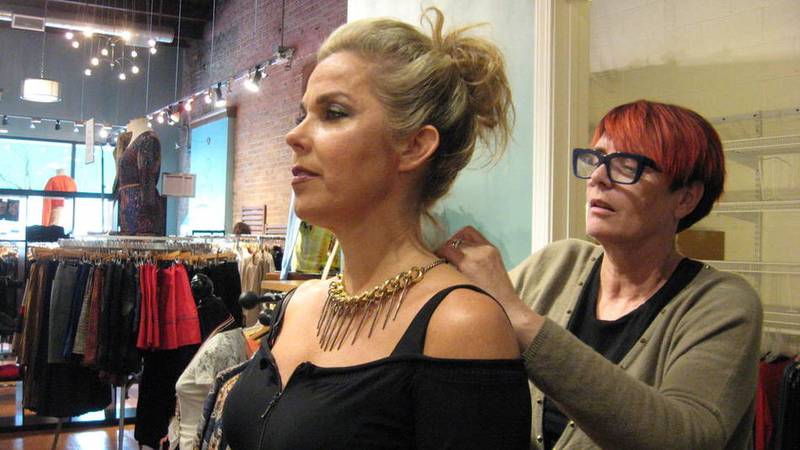 Sylvie Baumann helps dress Suzanne Positano at her Geneva store, C'est la vie by Sylvie. Positano, of St. Charles, will be in a fashion show this weekend. Baumann said she is closing both her retail store and spa because she is moving.