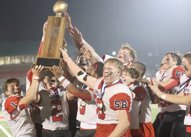 Members of the Amboy/LaMoille/Ohio football team hoist the 8-man I8FA championship trophy after defeating Polo 30-20 on Friday, Nov. 21, 2025 at April Zorn Memorial Stadium in Monmouth.