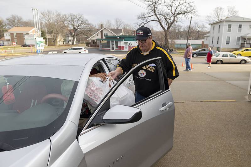 Dennis Hendricks distributes meals to one of the first customers in line Thursday, Nov. 24, 2022 at the Kaycee Hall in Dixon.