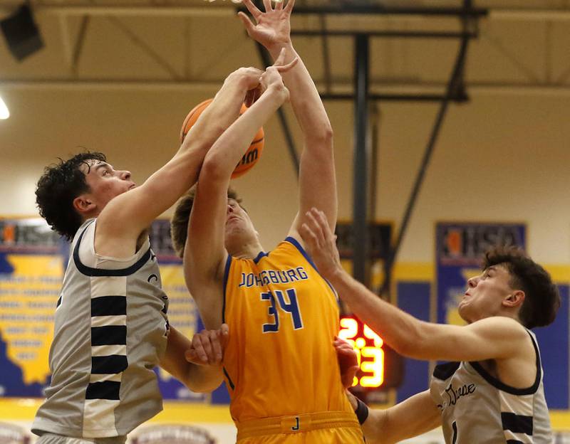Johnsburg's Danny Loud is fouled as he drives to the basket between Cary-Grove's Adam Bauer (left) and Cary-Grove's Dylan Dumele (right) during a Johnsburg Thanksgiving Tournament boys basketball game on Monday, Nov. 24, 2025, at Johnsburg High School.