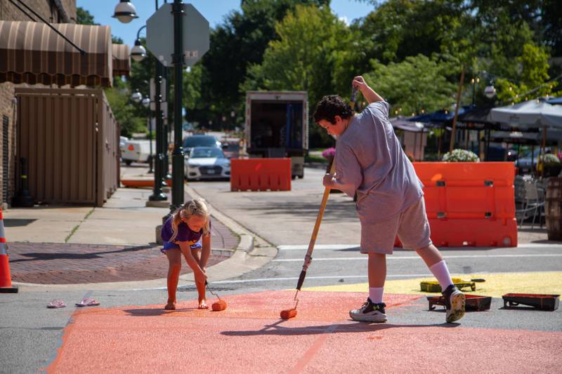 Avery Wallace, 6, left, and Henry Madigan, 10, paint the intersection of Riverside Avenue and Walnut Street in St. Charles at the Paint the Riverside event hosted by the St. Charles Arts Council on Saturday, July 30, 2022.