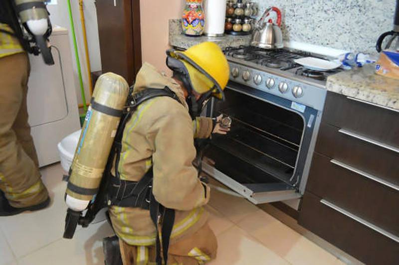 In this photo provided by the Quintana Roo Prosecutors Office, a firefighter examines a gas stove in the rented condo where an Iowa couple and their two children died in Tulum, Mexico. Mexican authorities said on Saturday, March 24, 2018 that autopsies indicate the Iowa couple and their two children died from inhaling toxic gas at the rented condo on Mexico's Caribbean coast, but there was no sign of foul play or suicide.