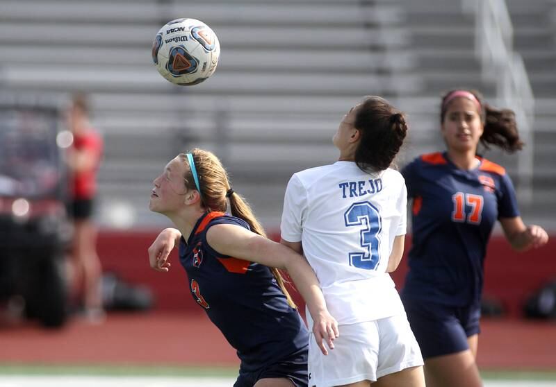 Oswego’s Gillian Young (left) heads the ball away from Geneva’s Kya Trejo during a Naperville Invitational game at Naperville Central on Saturday, April 23, 2022.