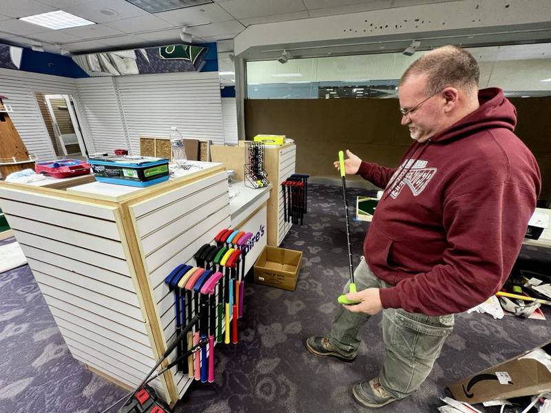 Owner Matthew Hicks holds a golf club inside his new business, The 9th Hole Mini Golf & More inside Sterling's Northland Mall.