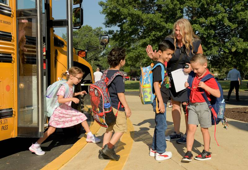 School social worker Lisa Maakestad greets students as they exit a school bus at Louise White Elementary School in Batavia for the first day of classes on Wednesday, Aug 14, 2025.