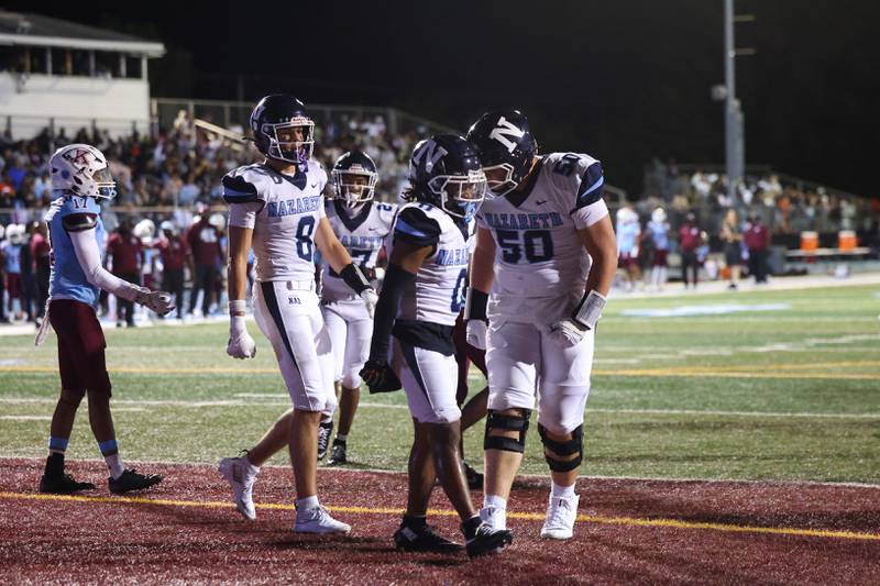 Nazareth's Eddie McClain, center, celebrates a touchdown catch with teammates Nate Sefcik, right, and Henry Sakalas during Nazareth's 33-12 victory over Kankakee on Friday, Aug. 29, 2025.