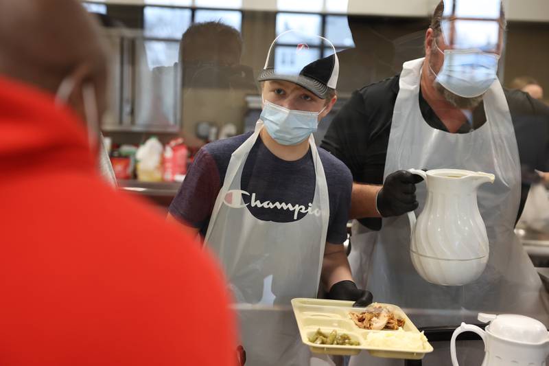 Tommy Cosgrove Jr. prepares a meal for a member of the community at the Daybreak Center on Thanksgiving Day in Joliet.