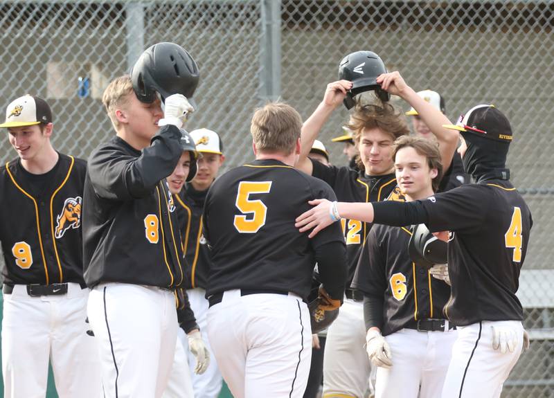 Members of the Riverdale baseball team congratulate teammate Dawson Peterson after hitting a home run against St. Bede on Monday, March 20, 2023 at St. Bede Academy.