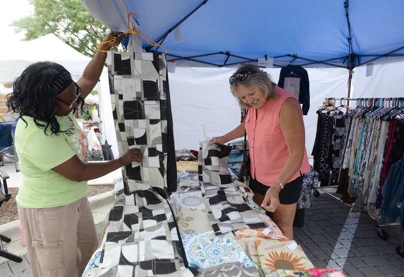 Owner of Sew Elegant of Wheeling assists Monica Parrilli of La Grange Highlands Vivian McFarland pick out fabric during the annual La Grange Craft Fair Saturday July 12, 2025.