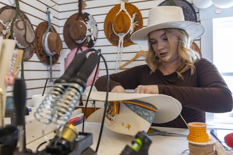 Marissa Hazell, shop owner at Hazell's Headdress crafts a custom made had for a customer during the opening of Market On Mill on May 3, 2025 in Utica, Illinois.