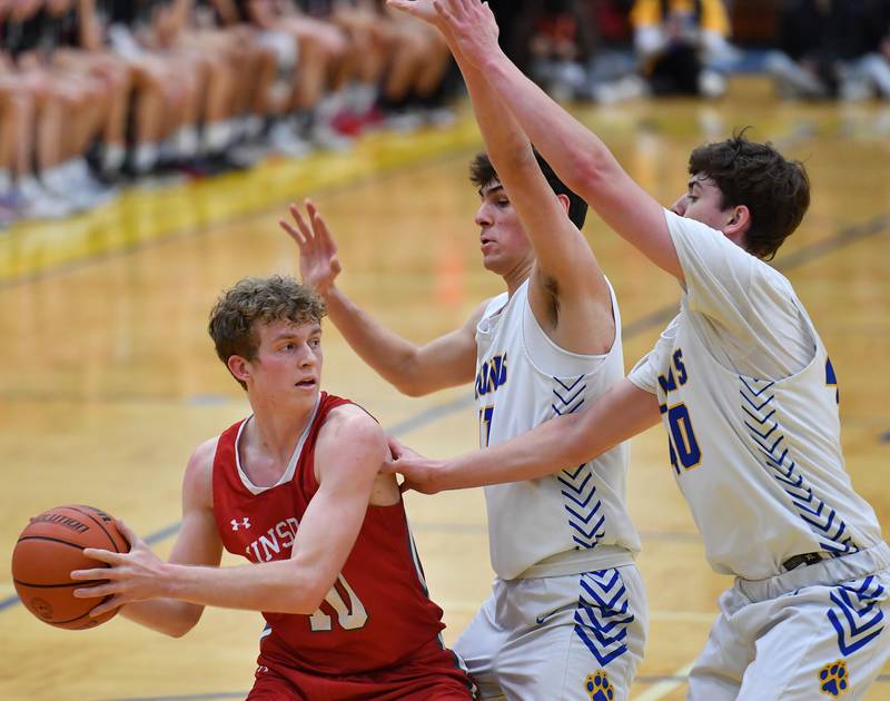 Hinsdale Central's Billy Cernugel starts to pass while double teamed by Lyons Township's Matthew DeSimone and Brady Chambers (right) during a game on Feb. 11, 2023 at Lyons Township High School in LaGrange.