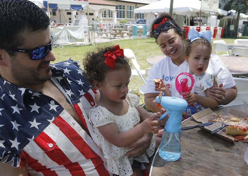 Joe and Kim Howard, with her daughters, Addison, 18 months, and Ava, 3, cool off with fans during Lakeside Festival on Thursday, July 3, 2025, on the grounds of the historic Dole Mansion in Crystal Lake,