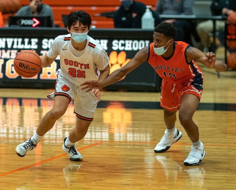 Wheaton Warrenville South's Micah Kim (22) dribbles the ball on the top of the key against Naperville North's Zeke Wiliams (12) during a game in Wheaton Feb. 5