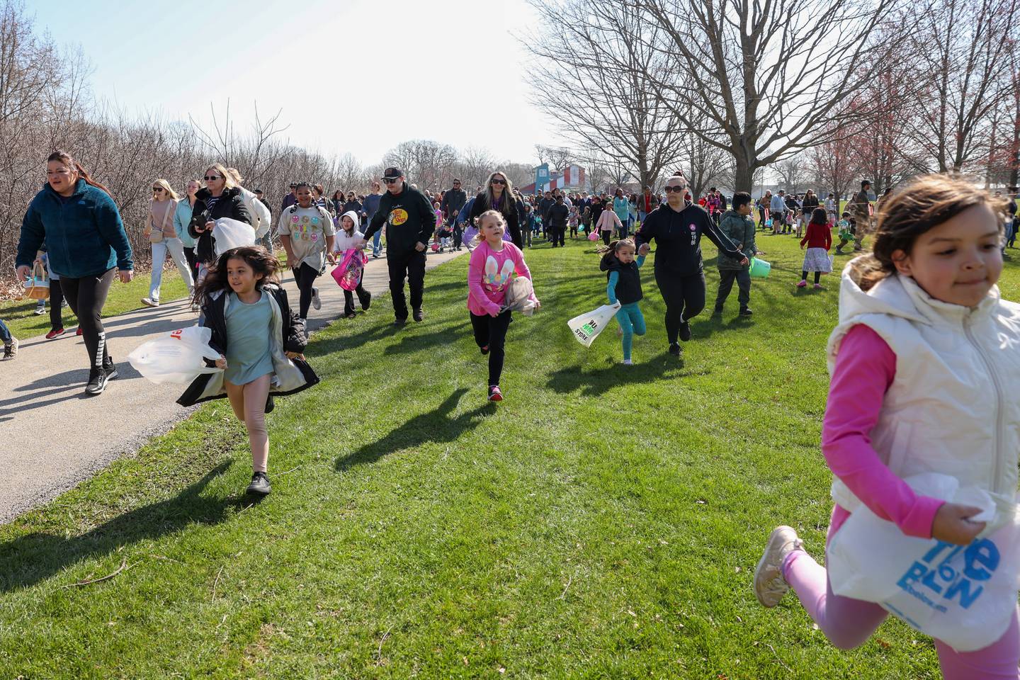 Children, followed by their adults, race into Perry Farm Park with hopes to collect as many of the 12,000 prize-filled, plastic eggs as possible during the annual Easter Egg Hunt on Saturday, April 12, 2025.