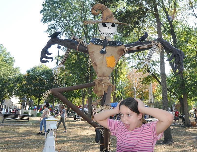 Kinzleigh Blair poses with a funny face in front of one of the many scarecrows at Washington Square Saturday during the annual Scarecrow Festival in Ottawa.