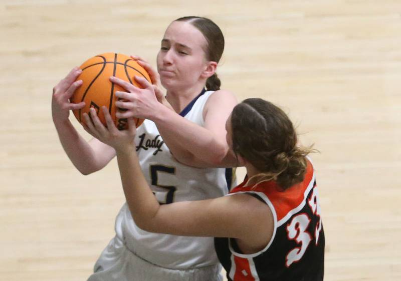 Marquette's Chloe Larson grabs a rebound over Roanoke Benson's Avery Alford on Thursday, Feb. 6, 2025 in Bader Gym at Marquette High School.