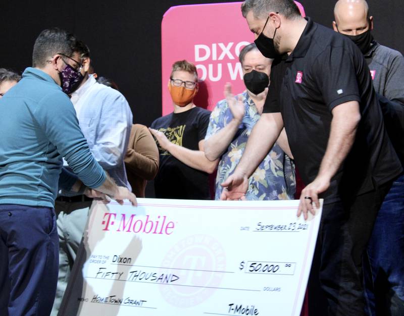 Jeremy England, executive director of Dixon Chamber and Main Street, at left, and T-Mobile representatives Dave Bradley and David Gidelski, right, complete the $50,0000 grant presentation while Dixon Historic Theatre director Tim Boles, center, applauds on Thursday, Sept. 23, 2021.