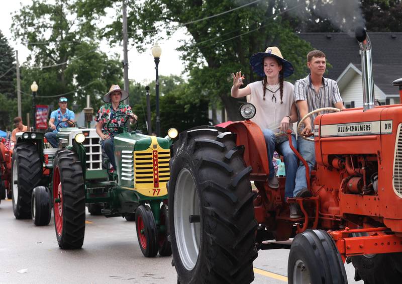 Vintage tractors drivers throw candy from their vehicles down Main Street Friday, July 4, 2025, during the Fourth of July parade in downtown Kirkland.