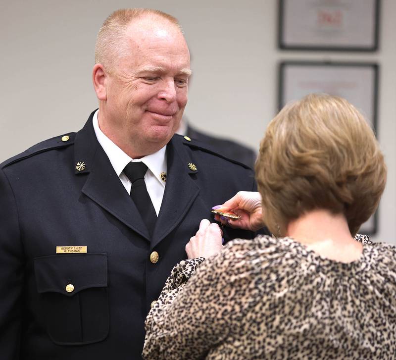 DeKalb Fire Chief Michael Thomas has his badge pinned on by his wife Jill after being sworn in as the city's new full-time fire chief Monday, April 11, 2022, during the DeKalb City Council meeting at the library. Thomas has been serving as the acting chief since the retirement of former chief Jeff McMaster in November.