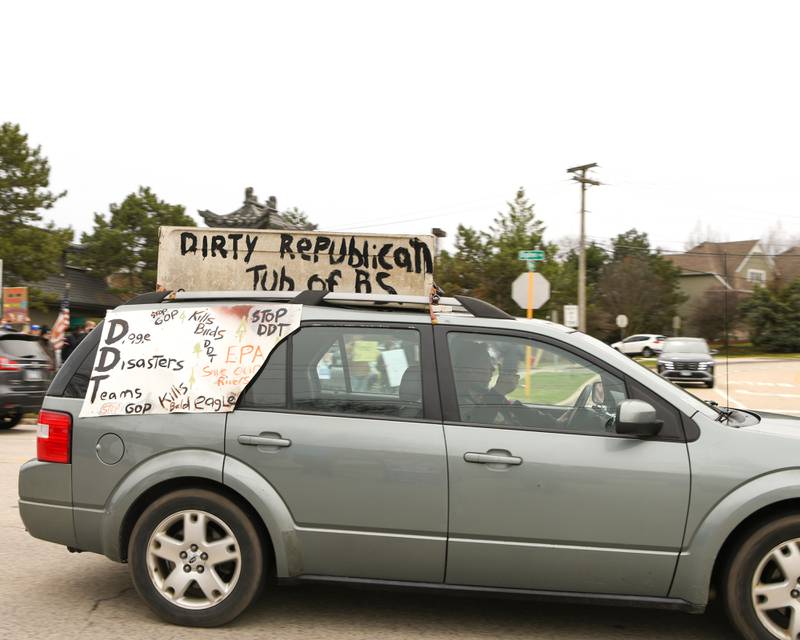 Vehicles drive by with signs during the Hands Off Demonstration held on Saturday April 5, 2025, held on Ogden Ave. in Lisle near the Tesla dealership.