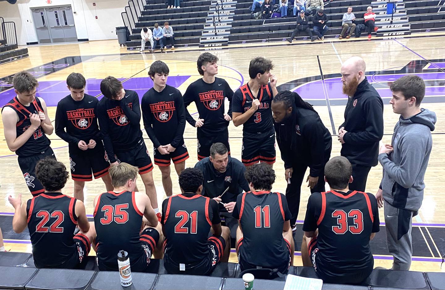 Lincoln-Way Central coach Brian Flaherty (kneeling at center) goes over things with his team during a timeout Thursday, Dec. 26, 2024, in Plano.