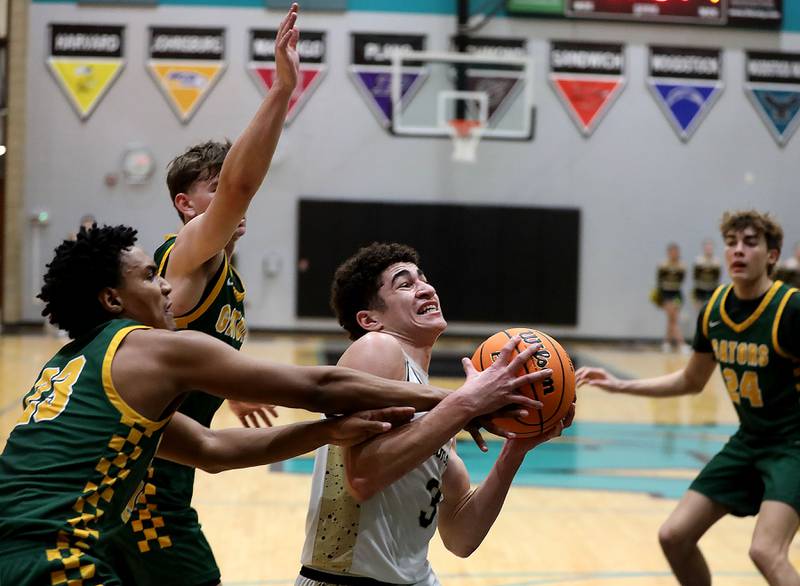 Sycamore's Marcus Johnson (right) drives between Crystal Lake South's David Mcfadden (left) and Nick Stowasser (center) during an IHSA Class 3A Woodstock North Sectional semifinal.basketball game on Wednesday, March 4, 2025, at Woodstock North High School.