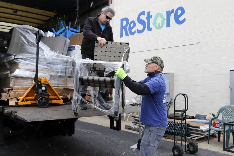 Jerry Cassidy, left, hands a stack of chairs off a truck filled with donations from Bob's Discount Furniture to Joe Dziedzic on Thursday, Nov. 18, 2021, at the Habitat for Humanity ReStore location in Woodstock.  A backlog of supplies at many retail furniture and home decor stores has contributed to an increase in shoppers purchasing their home furnishings from antique, thrift, and secondhand stores.