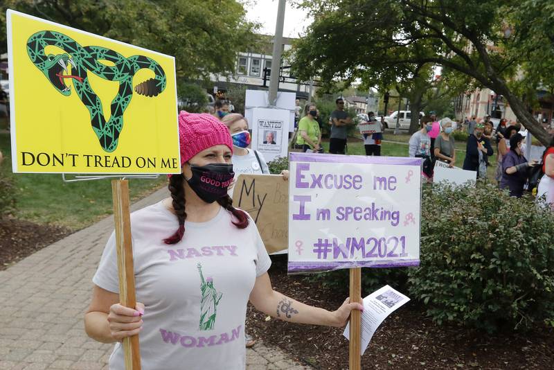 Laura Bell, of Crystal Lake, holds her signs as she and other attendees listen to speakers during a rally for abortion rights on the historic Woodstock Square on Saturday, Oct. 2, 2021, in Woodstock.