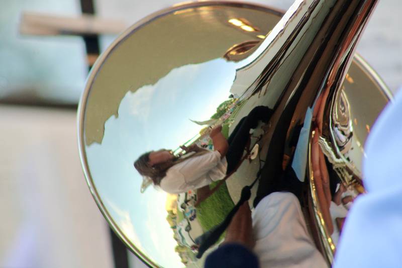 Other trombone players are reflected in the bell of a brass instrument during the Dixon Municipal Band Summer Series concert Thursday at Page Park.