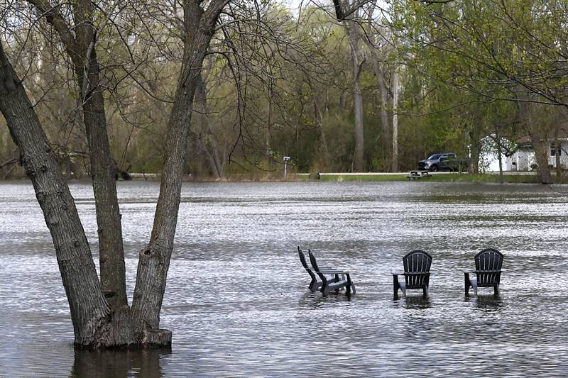 Four partially submerged chairs along South Wright Road near Burton’s Bridge on Sunday, April 19, 2026, as the Fox River continues to rise.