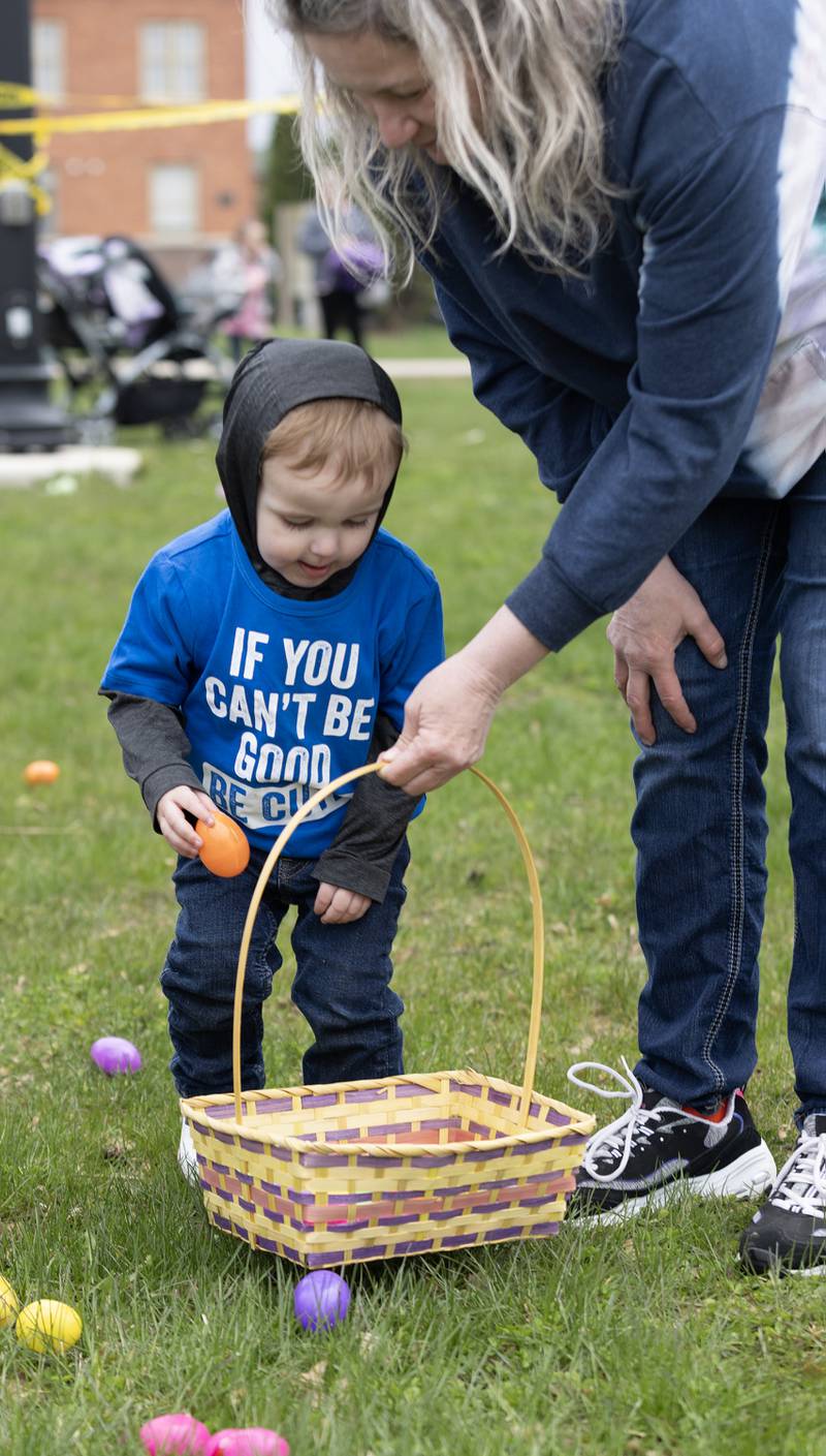 Cade Petry, 3, adds an orange egg to his basket Saturday, March 30, 2024, held by his grandmother, Kayla Kain of Ottawa.
