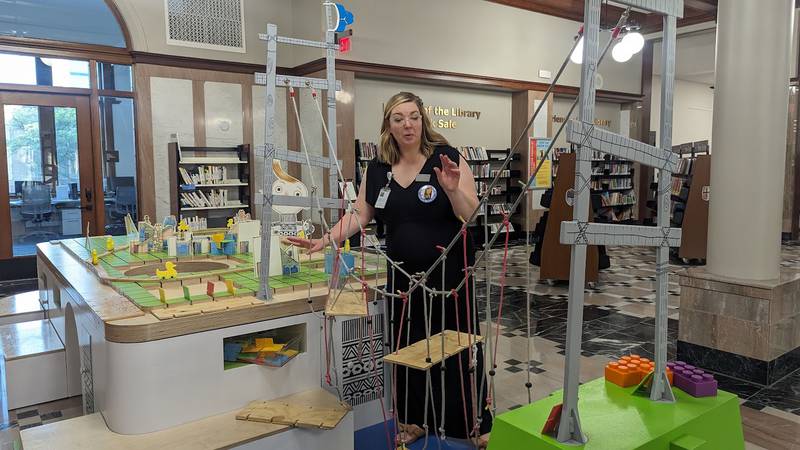 Mallory Hewlett, communications manager at the Joliet Public Library, shows one of the interactive displays in the “The Questioneers: Read. Question. Think. PLAY!” exhibit on Wednesday, June 21, 2023. This exhibit is based on the Questioneers book series authored by Andrea Beaty and illustrated by David Roberts. This traveling exhibit featuring the Questioneers characters opened June 16 at the Ottawa Street branch of the Joliet Public Library and is available during library hours through July 29.