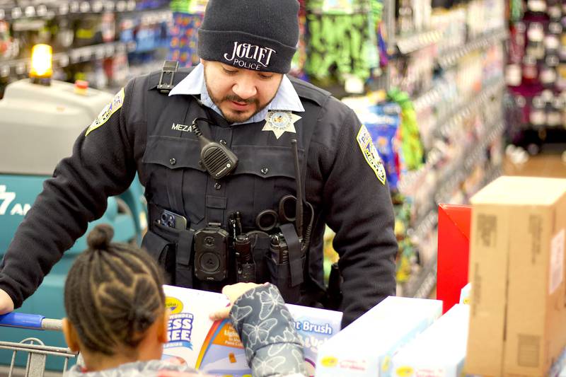 Joliet Police Officer Christopher Meza shops with a child during the 36th annual Santa's Cops event on Saturday, Dec. 6, 2025, at Walmart, 401 Illinois Route 59, in  Shorewood.