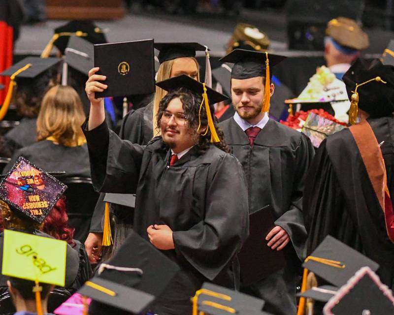 A Northern Illinois University graduate shows off his diploma as he walks back to his seat during the graduation ceremony on Saturday May 9, 2026, held at the Convocation Center in DeKalb.