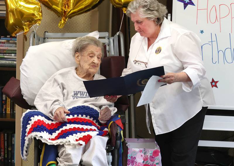 World War II veteran Myrtle Annetta Lusiak is presented with a gift and informed of a medal she will be receiving by Charlotte Hodder, with the DeKalb American Legion and AMVETS Thursday, May 2, 2024, during her birthday celebration at Aperion Care in DeKalb. Lusiak, who turned 107-years-old, was honored by DeKalb officials, veterans and other local groups Thursday for her service in the Women’s Army Corps from Aug. 5, 1943 until her honorable discharge on Nov. 27, 1945.