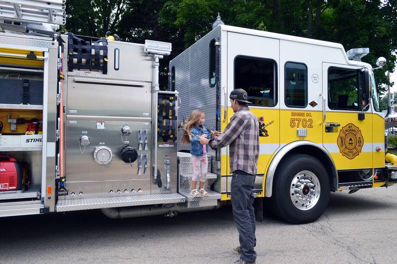Thomas Bradshaw, of Mt. Morris, helps 5-year-old Madeline Heathcott off a Mt. Morris firetruck on Tuesday, Aug. 6, 2024, during Mt. Morris' first National Night Out.
