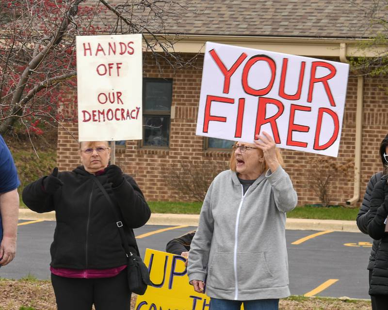 Carol of Wheaton, left, and June of Bolingbrook hold signs during the Hands Off Demonstration outside the Tesla dealership on Ogden Ave. on Saturday April 5, 2025, held in Lisle.