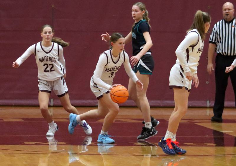 Marengo’s Maggie Hanson, center, drives a fast break as sisters Sophie, left, and Katie, right, prepare to run against Woodstock North in varsity girls basketball on Tuesday, Dec. 2, 2025, at Marengo High School in Marengo.