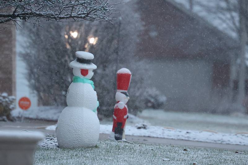 Holiday lawn decorations sit on a lightly snow covered yard in a Joliet subdivision.